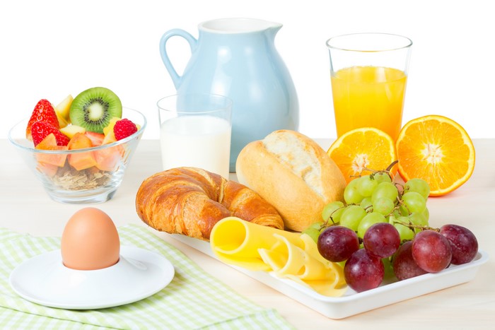Breakfast with fruit, croissant, bread, cheese, and drinks