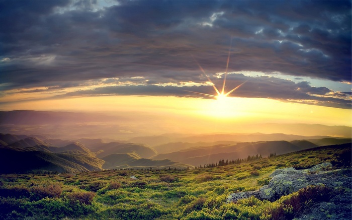 Sunrise over misty mountains and grassy hills