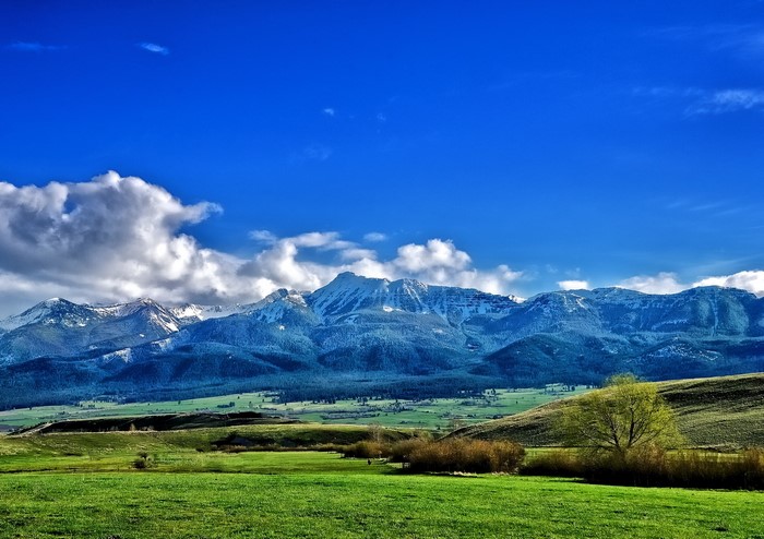 Snow-capped mountains and green fields under a blue sky