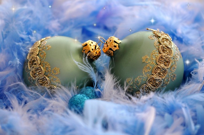 Two Christmas ornaments with blue feathers
