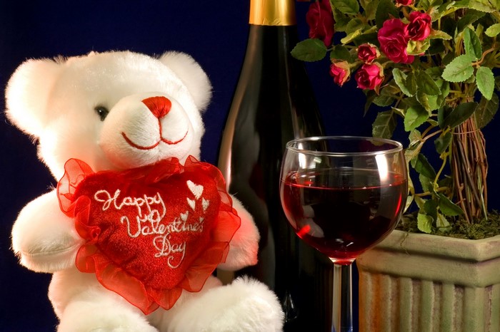White teddy bear holding a heart with wine and roses