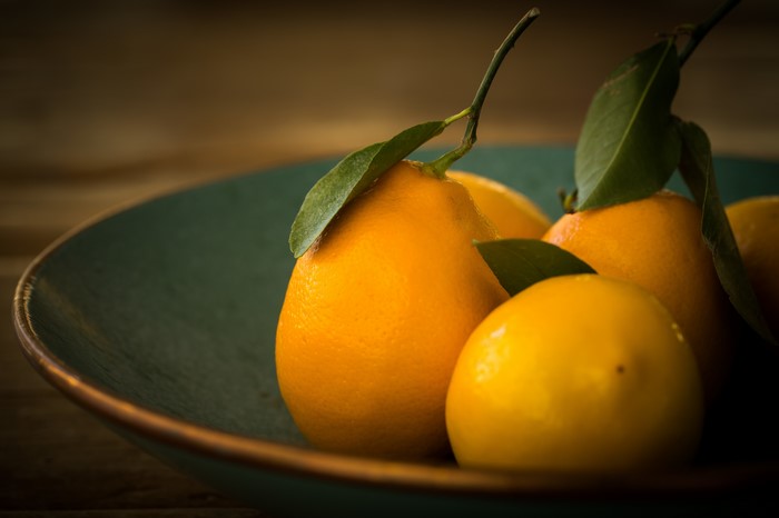 Lemons and oranges with leaves in a bowl