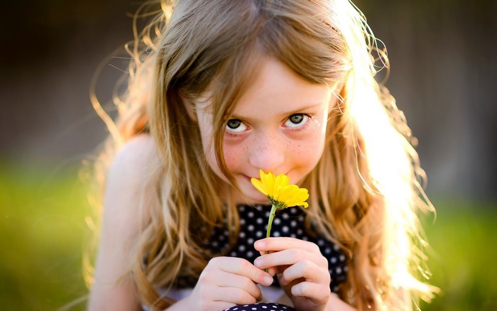 Young girl smelling a yellow flower
