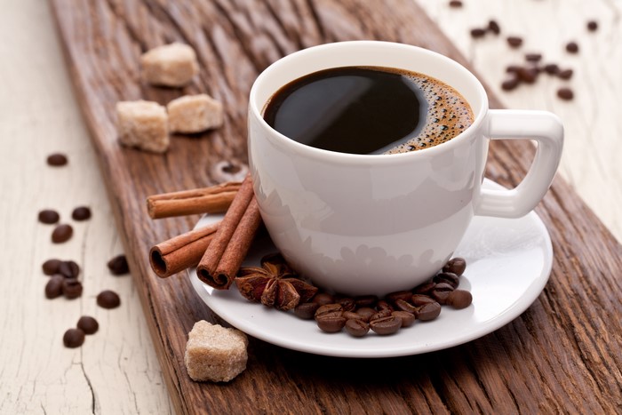 Coffee cup with cinnamon sticks and sugar cubes