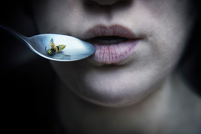 Close-up of lips and a spoon with a wasp
