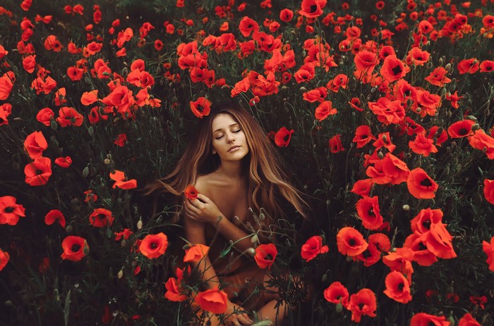 Woman lying in a field of red poppies