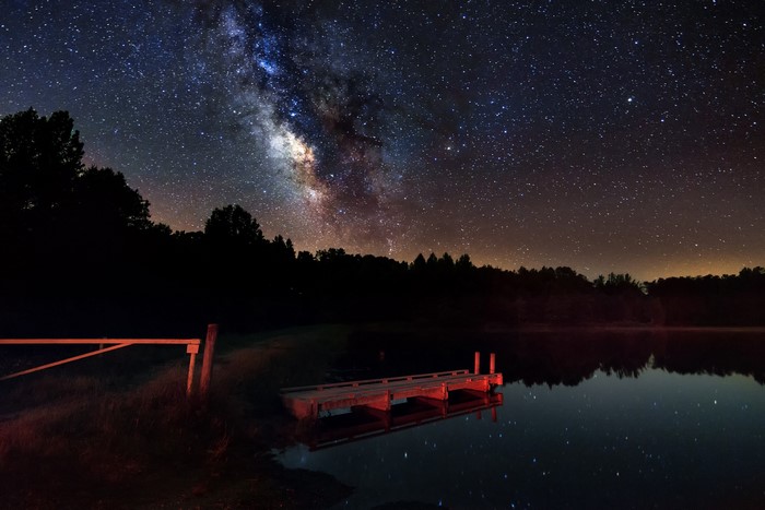 Milky Way over a lake with a dock at night