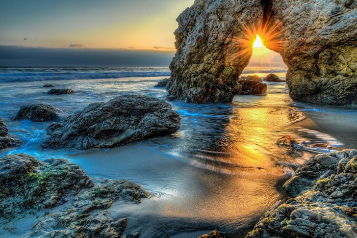 Sunset through rock arch at Malibu beach