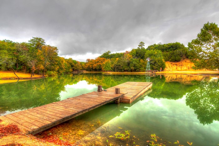 Wooden dock on a pond with trees and a windmill