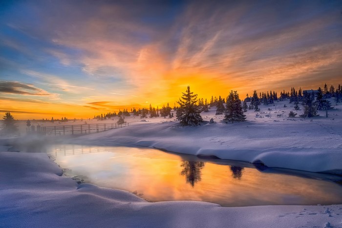 Winter sunset over snowy landscape with a river
