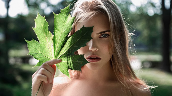 Woman holding a maple leaf in front of her face