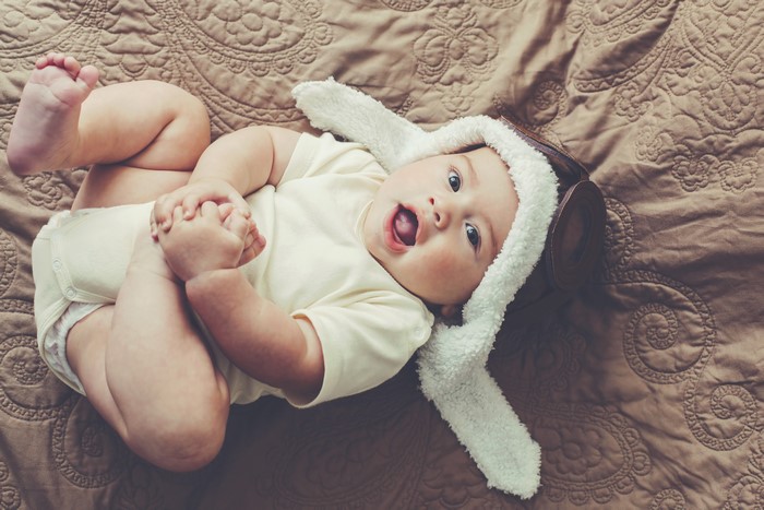 Baby wearing a winter hat lying on a blanket