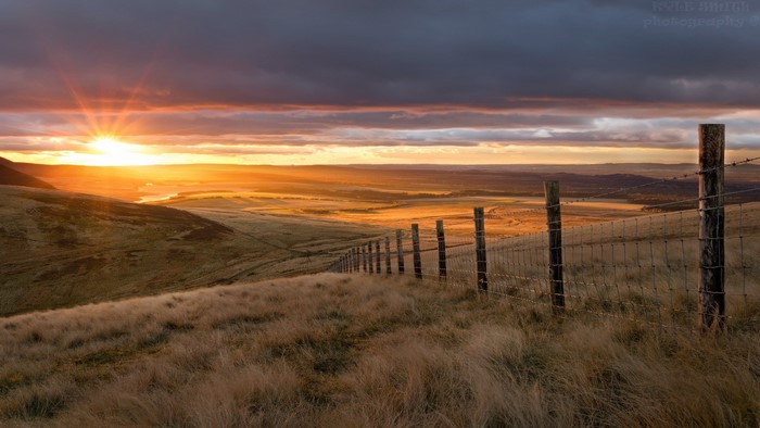 Sunset over a rural landscape with a fence