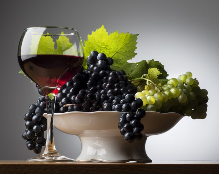 Red wine and grapes in a bowl with leaves