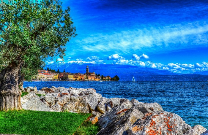 Lakefront town with mountains and sailboat