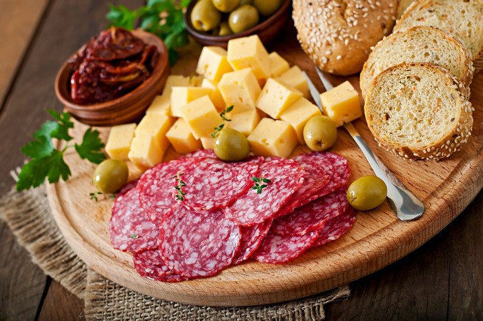 Charcuterie board with salami, cheese, olives, sun-dried tomatoes, and bread