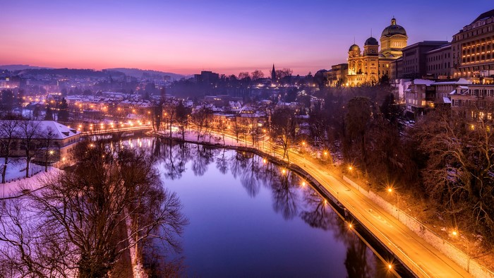 Bern, Switzerland at twilight with river and illuminated buildings