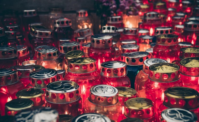 Many red glass candle jars with lit flames