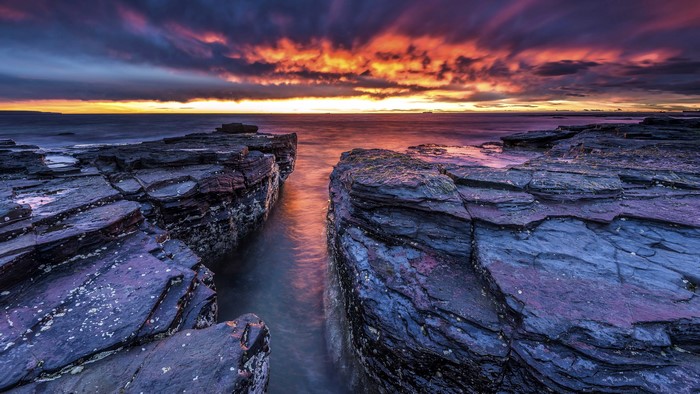 Sunset over rocky coast with dramatic clouds