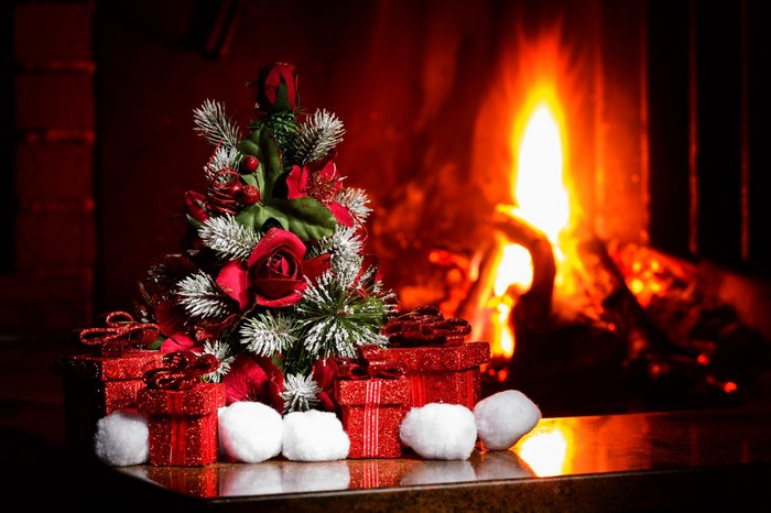 Christmas tree with gifts by a fireplace