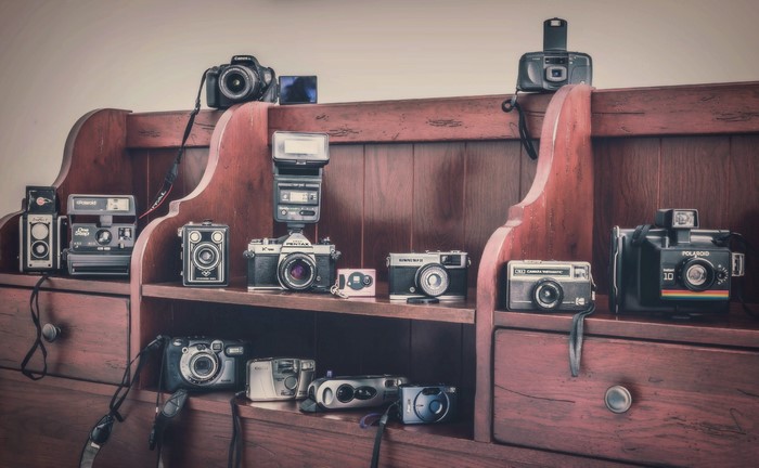 Collection of vintage and modern cameras on a wooden shelf