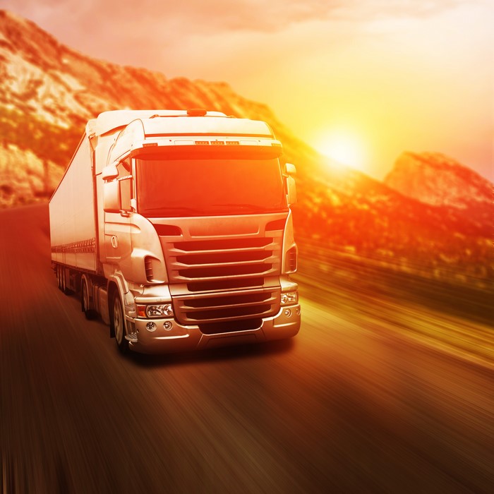 White truck driving on a road during sunset