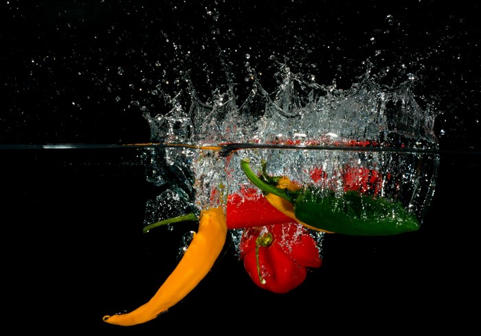Colorful peppers splashing into water