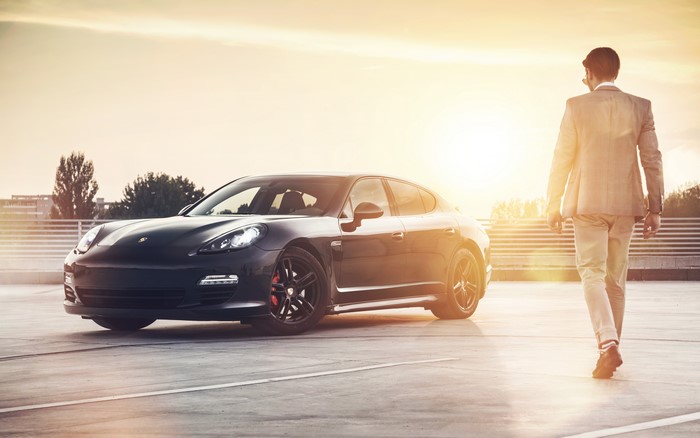 Man in suit walking next to Porsche Panamera