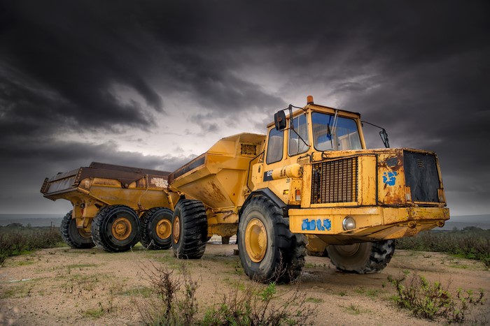 Two old yellow articulated dump trucks