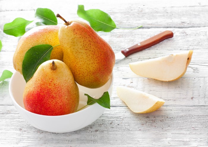 Pears in a bowl with leaves and a knife