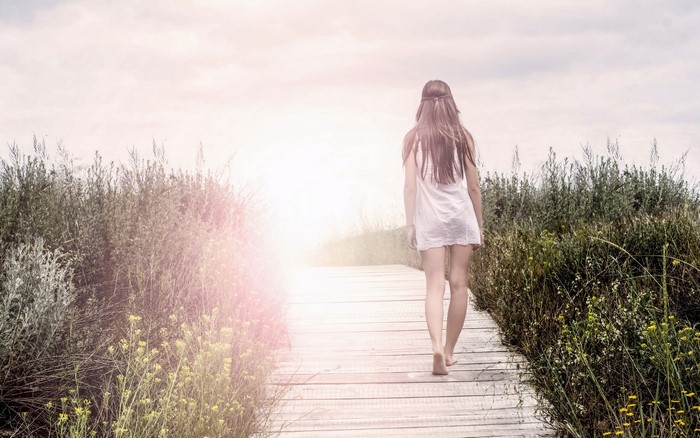 Woman walking on a boardwalk through tall grass