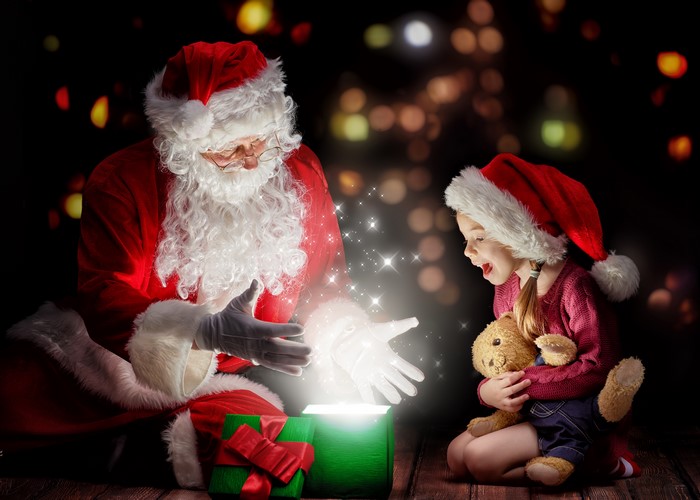 Santa Claus giving a gift to a girl with a teddy bear