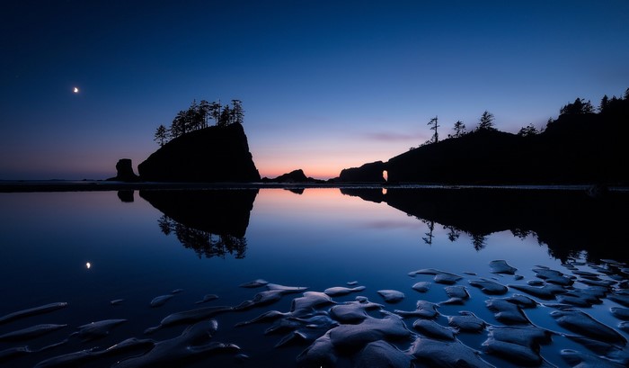 Moonlit beach with rock formations and reflection