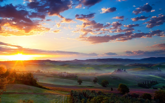 Tuscany landscape at sunrise with rolling hills and clouds