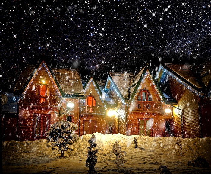 Wooden houses decorated with lights in the snow at night