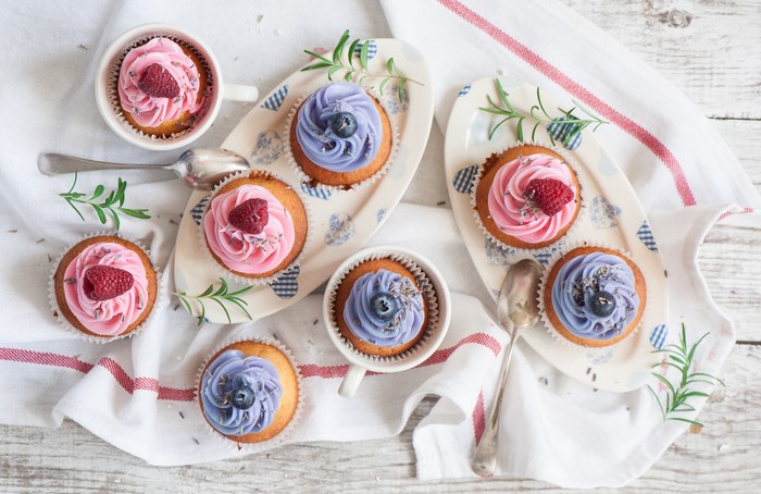 Cupcakes with pink and purple frosting on plates and in cups