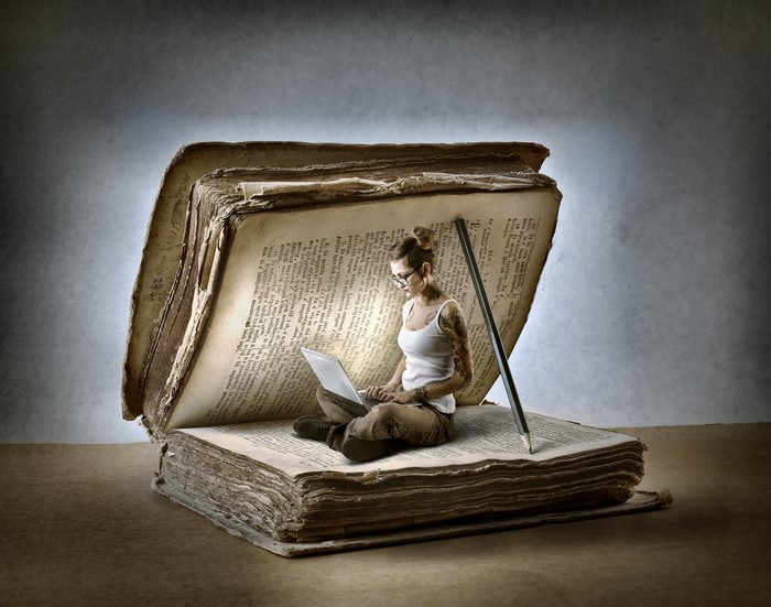 Woman with laptop inside a giant book