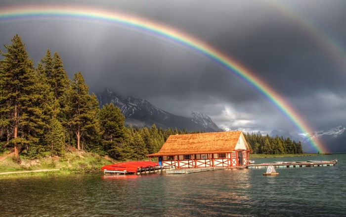 Boathouse on a lake with a double rainbow