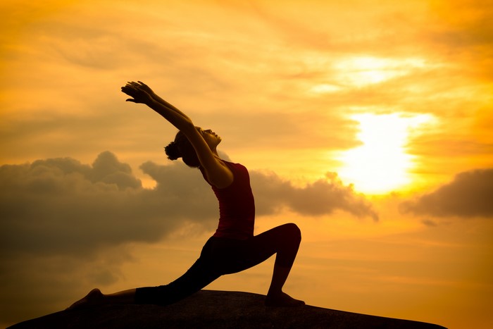 Woman practicing yoga at sunset