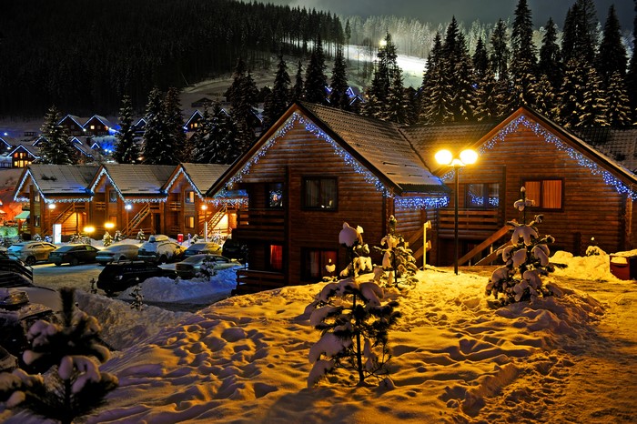Wooden houses with Christmas lights in the snow at night