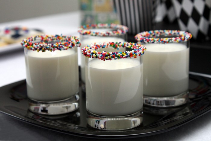 Four glasses of milk with sprinkles on a black tray