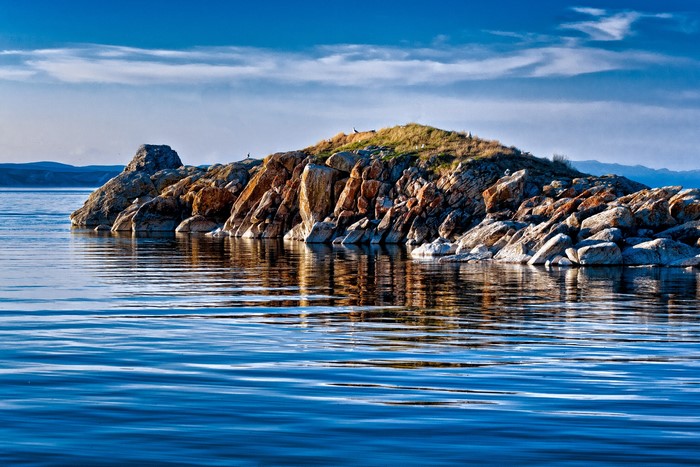 Rocky island in a blue lake under a cloudy sky
