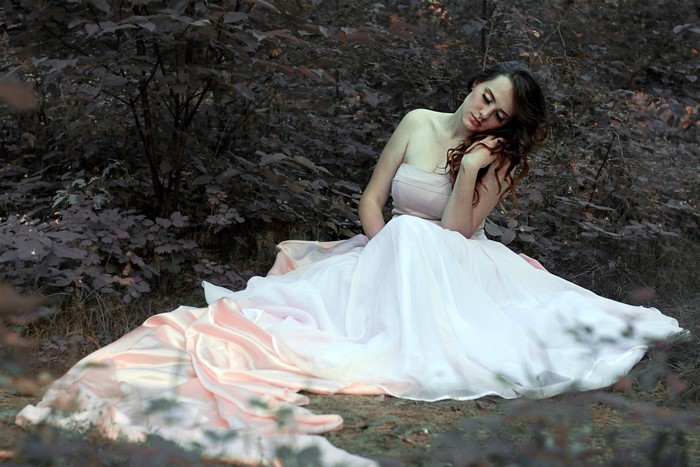 Woman in a flowing dress sitting in a forest
