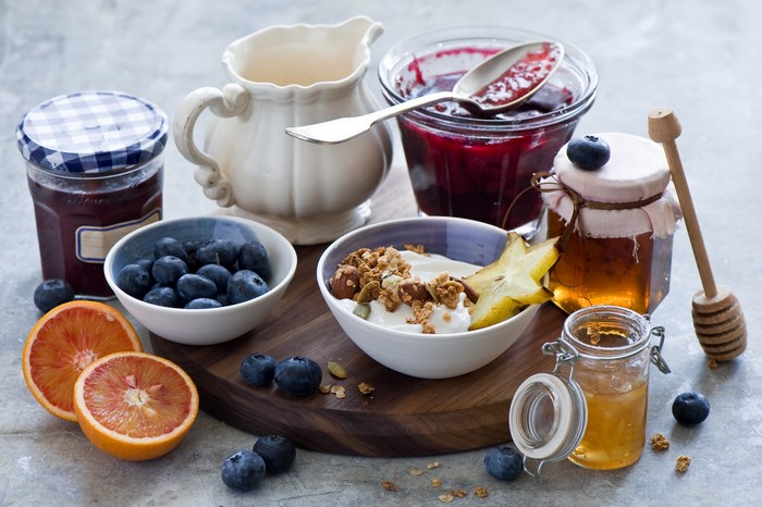Breakfast spread with muesli, yogurt, berries, jam, honey, and oranges