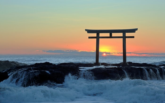 Torii gate at sunrise over the sea in Japan
