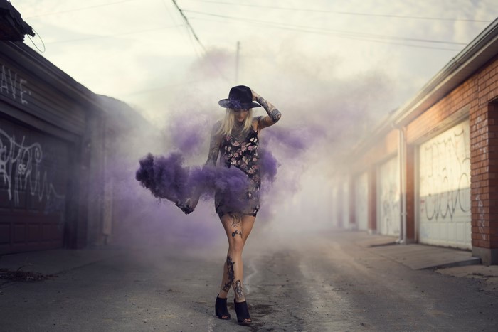 Woman with tattoos and purple smoke bomb