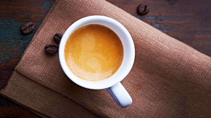 Espresso coffee cup with beans on burlap