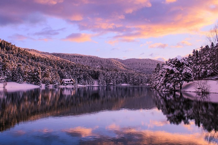 Snowy lake and forest with colorful sunset sky