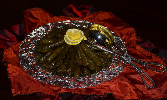 Dolmades with lemon slices and serving tongs
