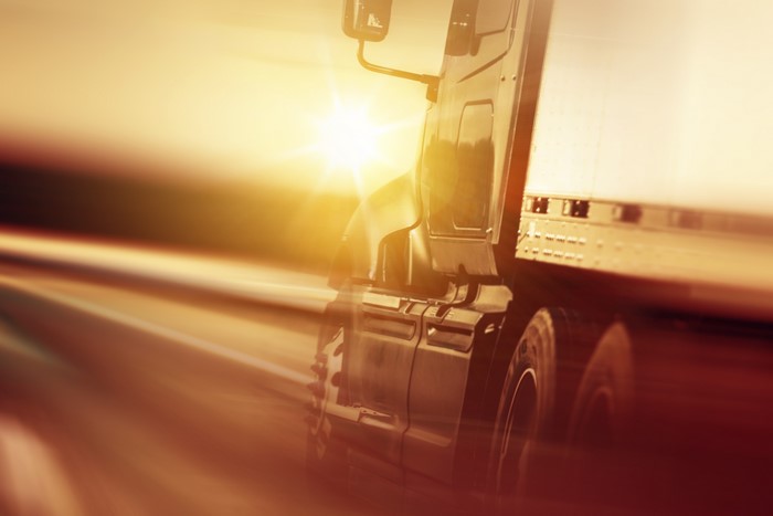 Truck driving on road with sun flare